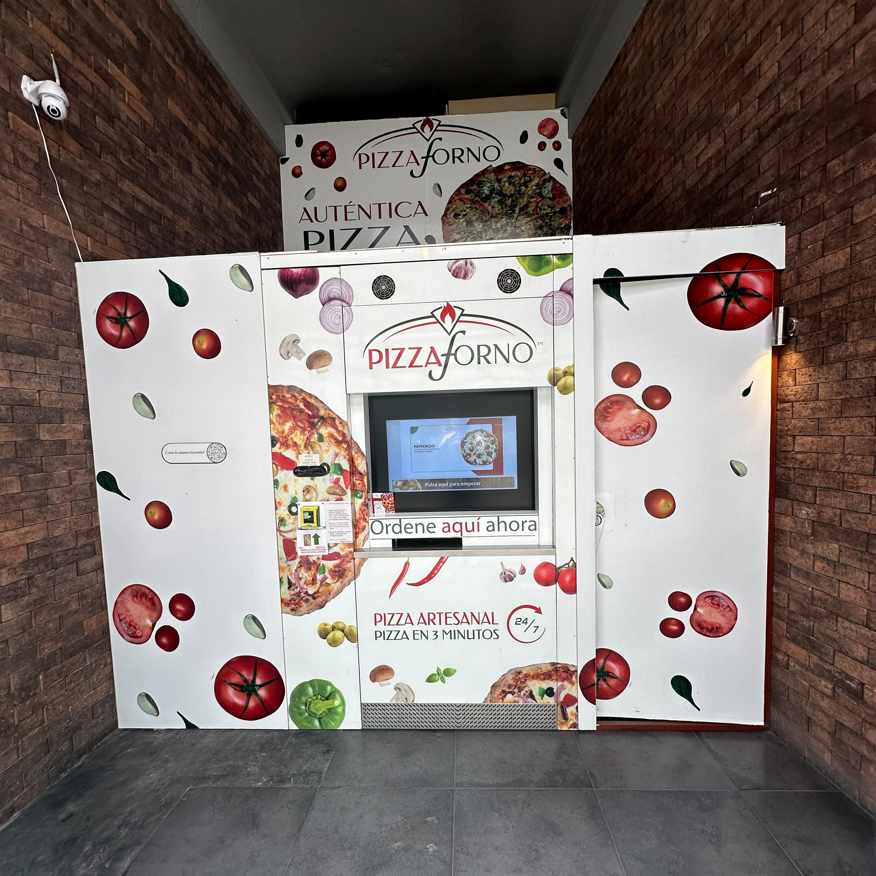 A PizzaForno machine in hallway with brick walls