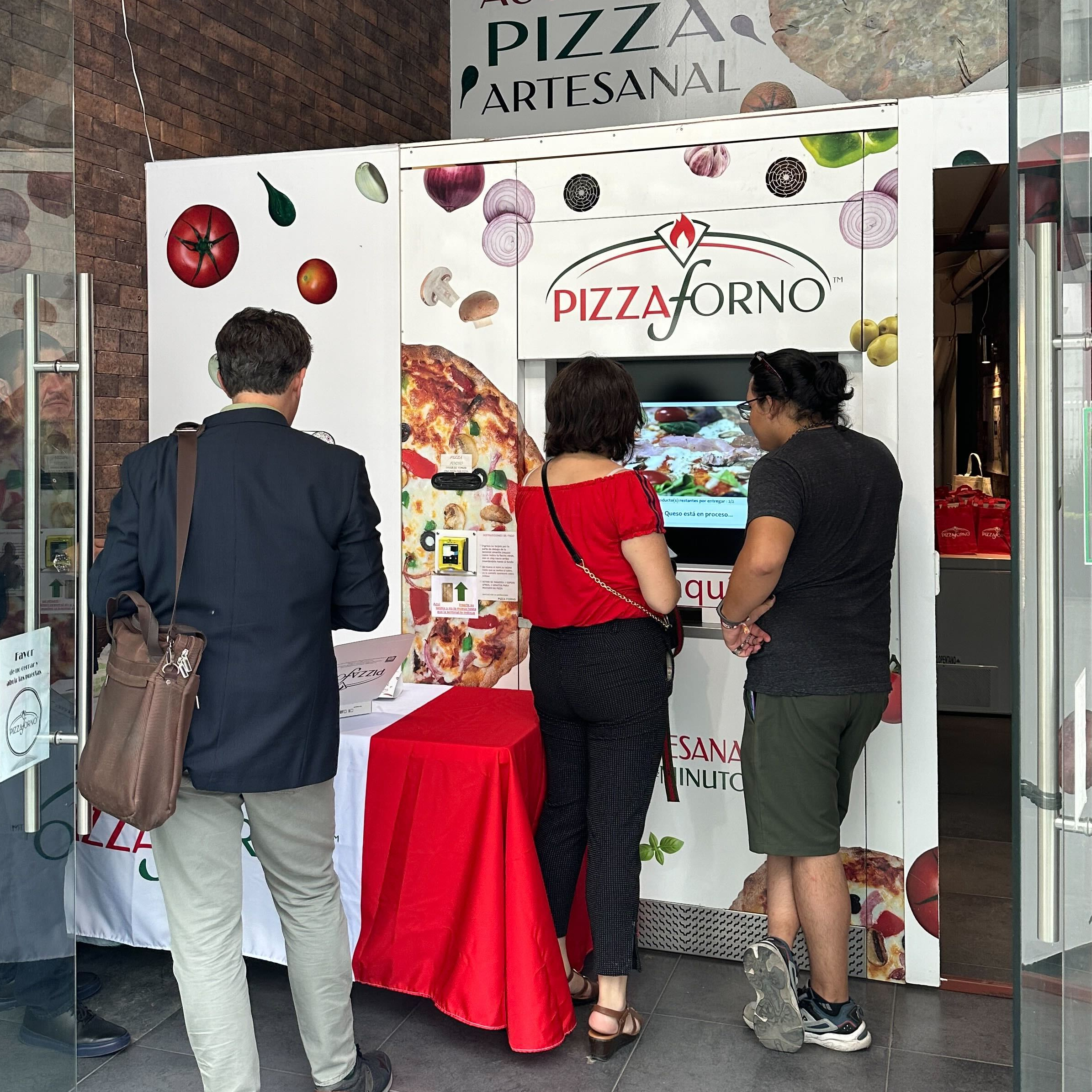 A group of people using the PizzaForno machine to order pizza